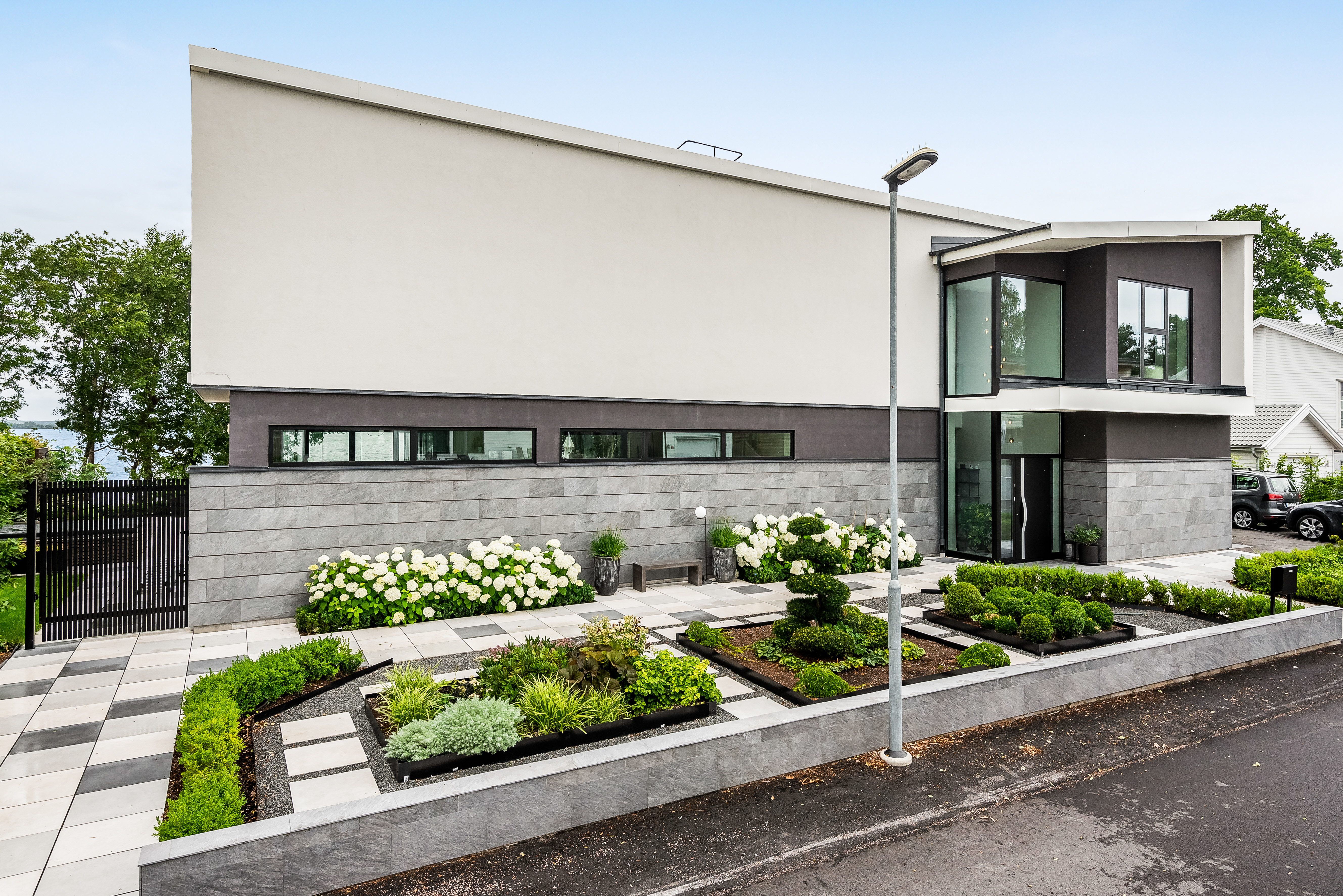 Modern stenhusfasad i funkisstil med entréparti och anlagd gård i Ekängen, Linköping